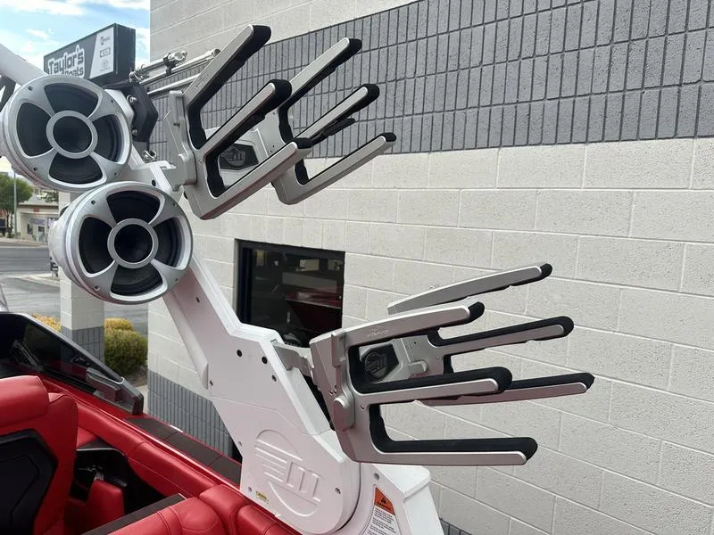 Slide: The Image of 2021 Malibu M240 boat with wakeboard racks and speakers, parked near a building. - 26