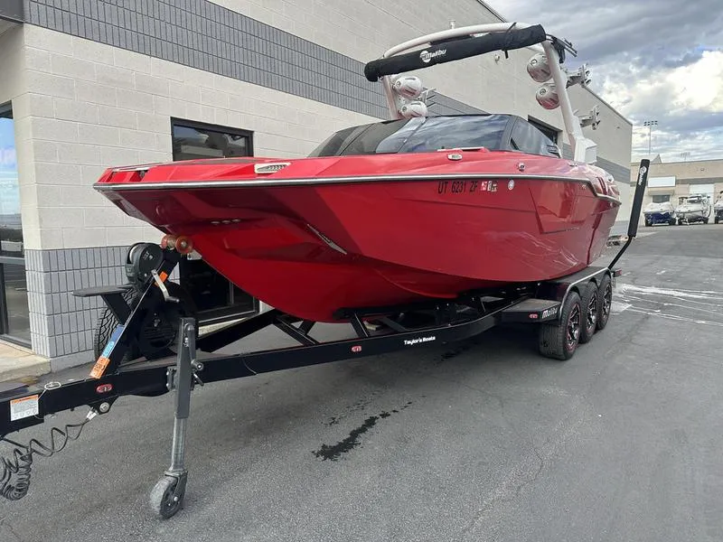 Slide: The Image of Red 2021 Malibu M240 boat on trailer, parked outside a building. - 7