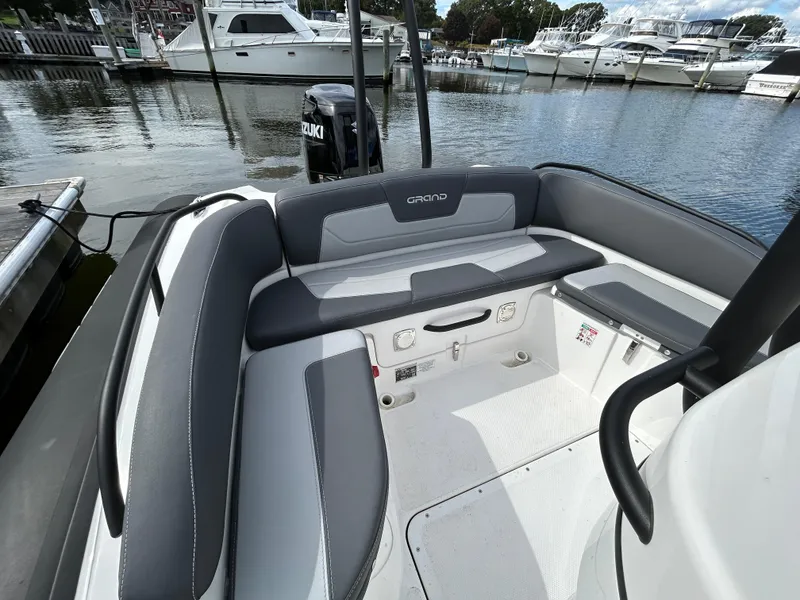 Slide: The Image of 2025 Grand Inflatables G850 boat interior with gray seating, docked at marina. - 13