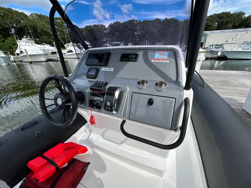 Slide: The Image of 2025 Grand Inflatables G850 boat dashboard with steering wheel and controls at marina. - 14