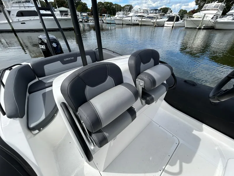 Slide: The Image of 2025 Grand Inflatables G850 boat interior with sleek seating at marina. - 19