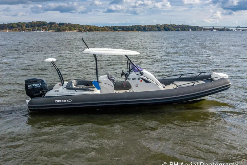 Slide: The Image of 2025 Grand Inflatables G850 boat on water, featuring Suzuki outboard motor. - 2