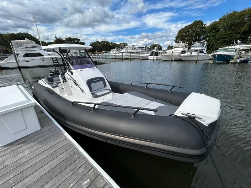 Slide: The Image of 2025 Grand Inflatables G850 boat docked in a marina, surrounded by other vessels. - 6