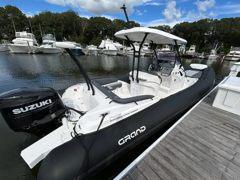 Slide: The Image of 2025 Grand Inflatables G850 boat docked, featuring Suzuki outboard motor, under clear sky. - 7