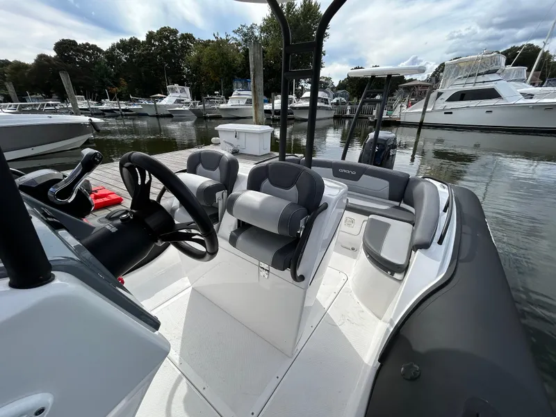 Slide: The Image of 2025 Grand Inflatables G850 boat interior at marina, featuring sleek seating and steering console. - 25