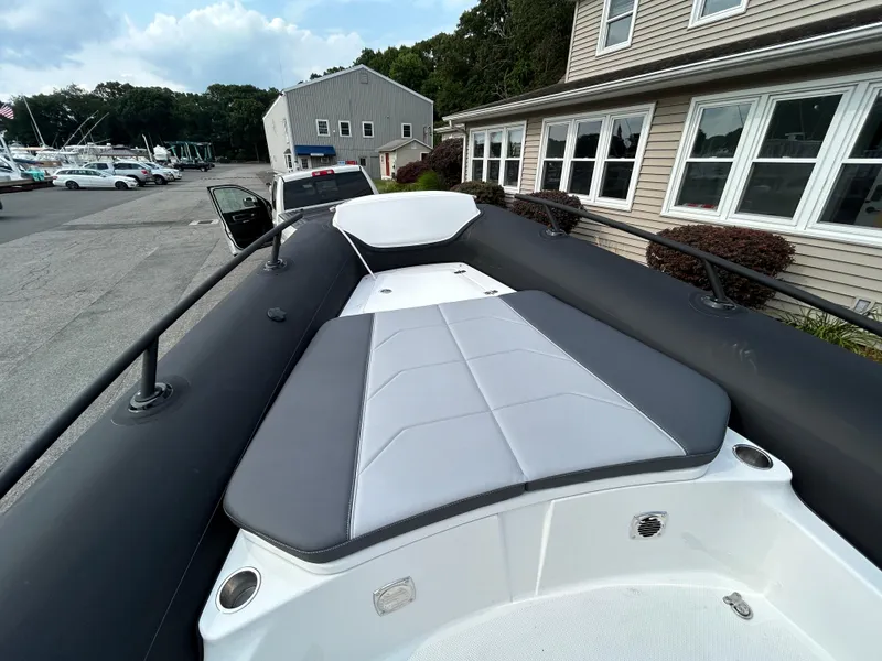 Slide: The Image of 2025 Grand Inflatables G850 boat with cushioned seating, docked near buildings. - 35