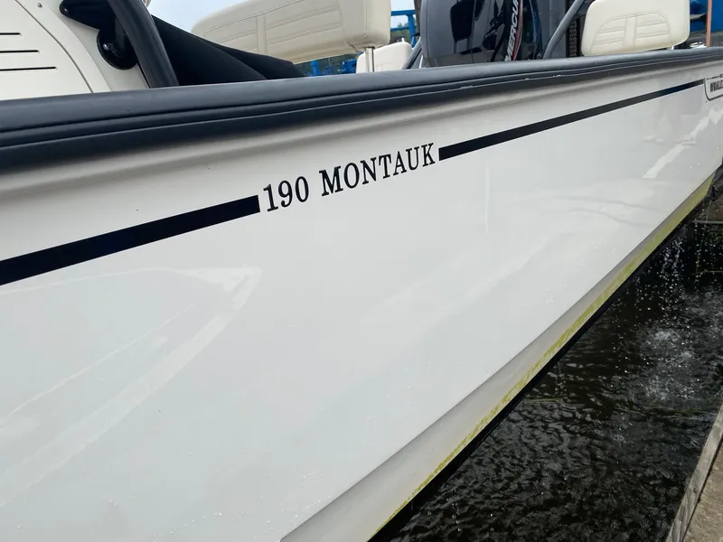 Slide: The Image of 2023 Boston Whaler 190 Montauk boat side view, white hull with black lettering. - 14