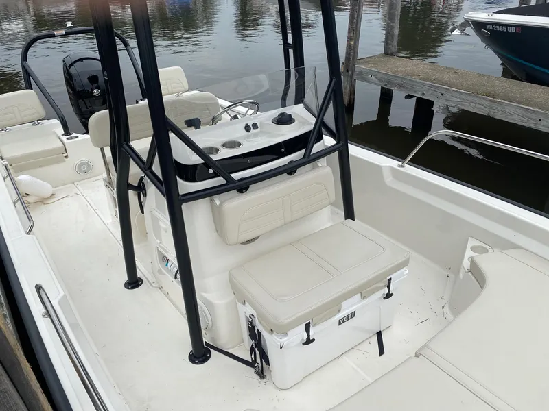Slide: The Image of 2023 Boston Whaler 190 Montauk boat interior with seating and console, docked by the water. - 18