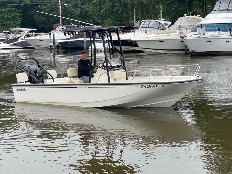 Slide: The Image of 2023 Boston Whaler 190 Montauk boat on calm water near a marina. - 3
