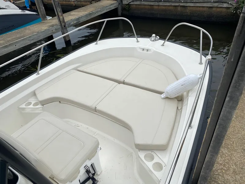 Slide: The Image of 2023 Boston Whaler 190 Montauk boat interior with cushioned seating at dock. - 7