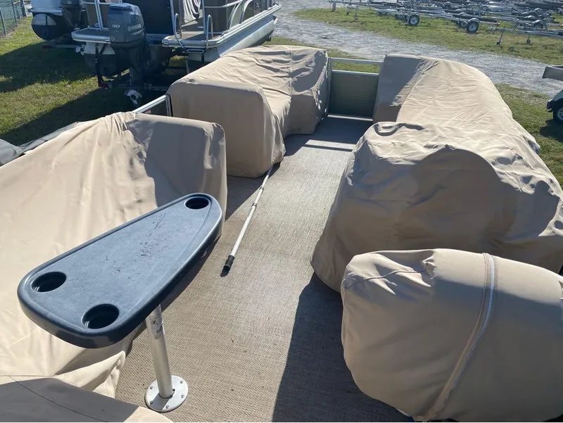 Slide: The Image of 2017 Bennington 22 SLX pontoon boat with covered seating and table, parked outdoors. - 12