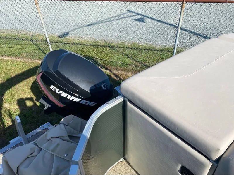 Slide: The Image of 2017 Bennington 22 SLX with Evinrude outboard motor, parked near a chain-link fence. - 3