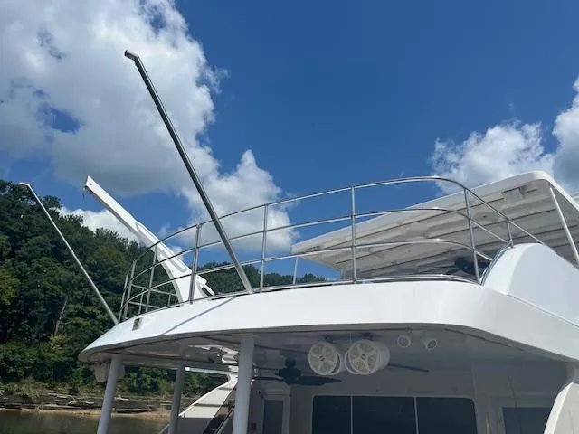 Slide: The Image of 2010 Stardust Cruisers houseboat under a clear blue sky with lush greenery. - 2