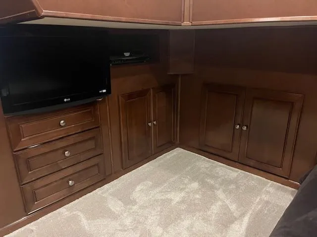 Slide: The Image of 2010 Stardust Cruisers houseboat interior with TV, wooden cabinets, and carpeted floor. - 29