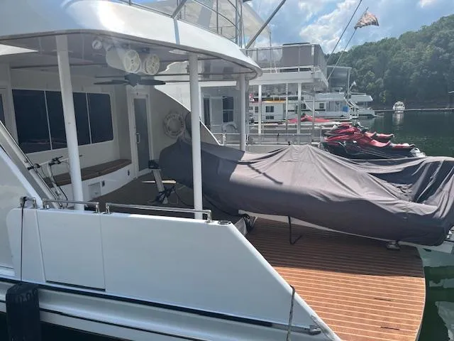 Slide: The Image of 2010 Stardust Cruisers houseboat with covered deck, docked near jet skis and scenic lake. - 4