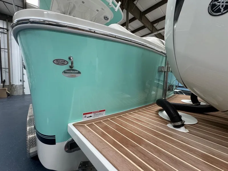 Slide: The Image of 2022 Regulator 25 boat with teal hull and wooden deck in a warehouse. - 48