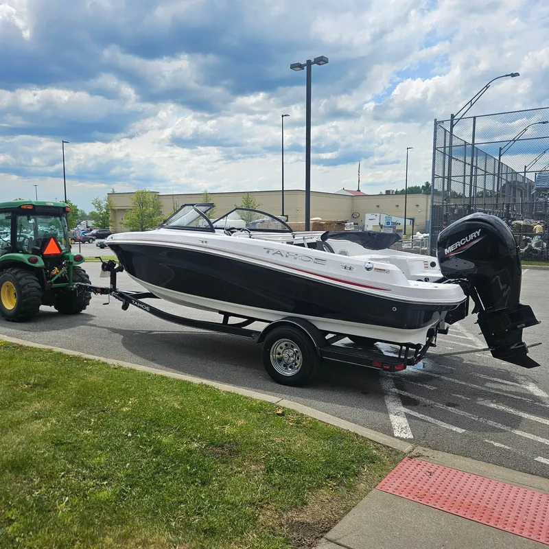 Slide: The Image of 2024 Tahoe 200 S boat on trailer, towed by a tractor in a parking lot. - 2
