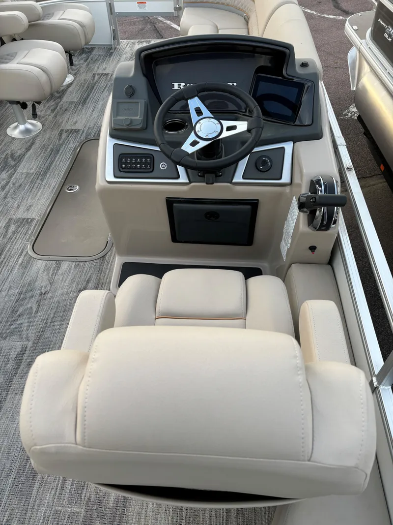 Slide: The Image of 2024 Ranger Reata 223FC boat interior with steering console and beige seating. - 8