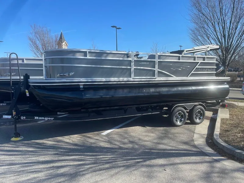 The Image of 2024 Ranger Reata 223C pontoon boat on trailer in parking lot. - 0