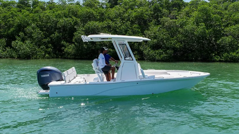 Slide: The Image of 2025 Sea Fox 231 Bay Fox boat cruising on clear water near lush greenery. - 2