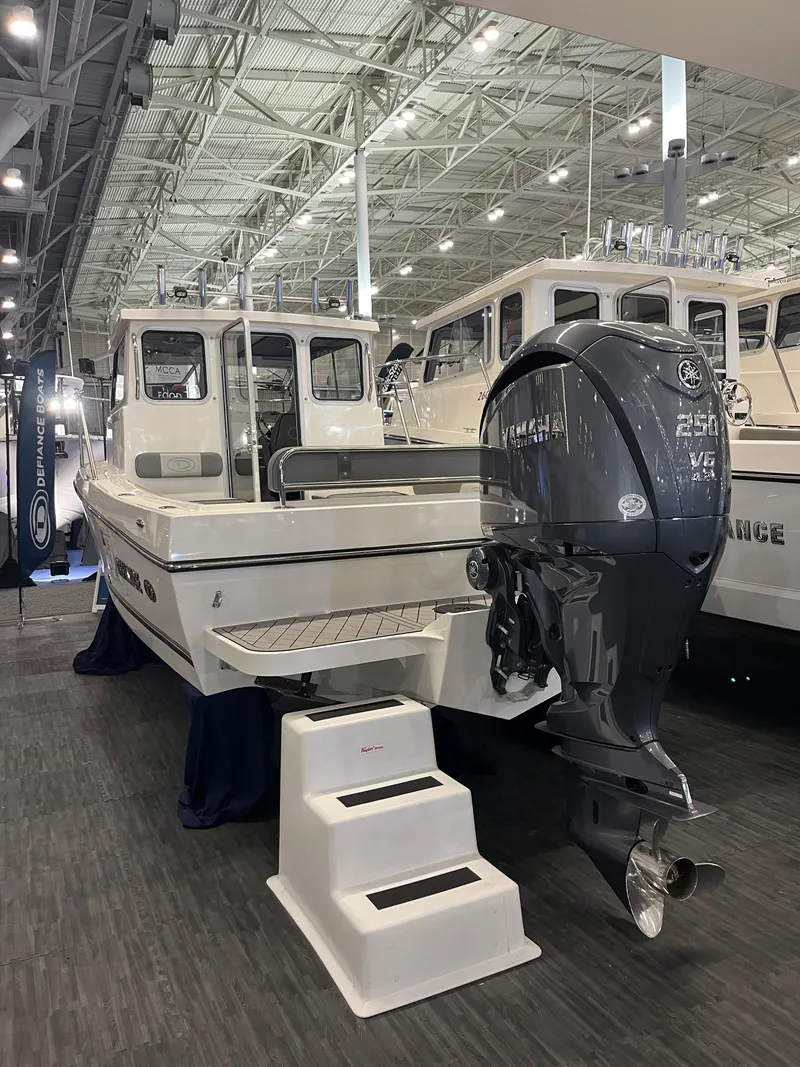 Slide: The Image of 2025 Defiance Admiral 220 EX boat with outboard motor displayed indoors. - 2