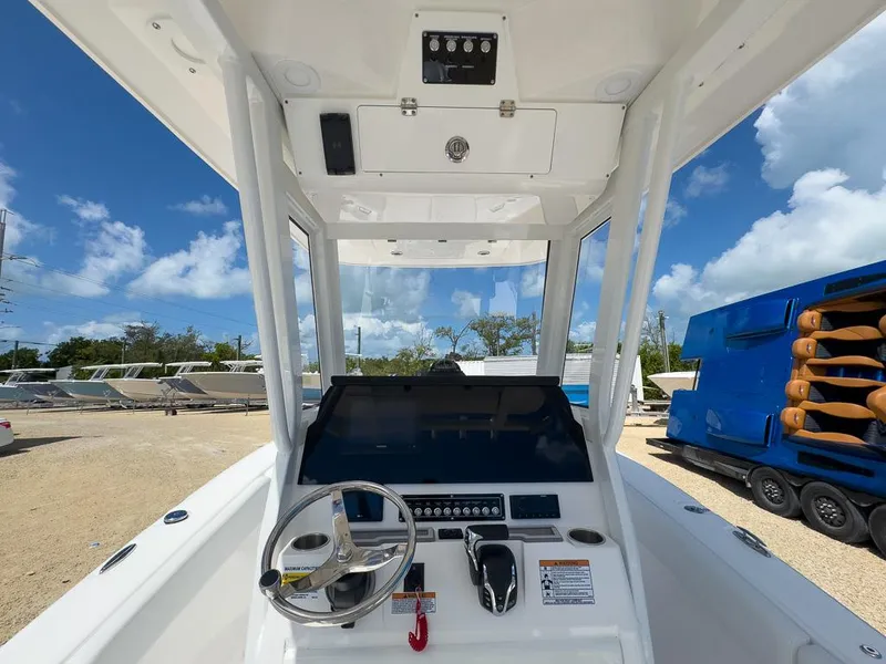 Slide: The Image of 2025 Sea Fox 248 Commander boat dashboard with steering wheel and controls under clear blue sky. - 14