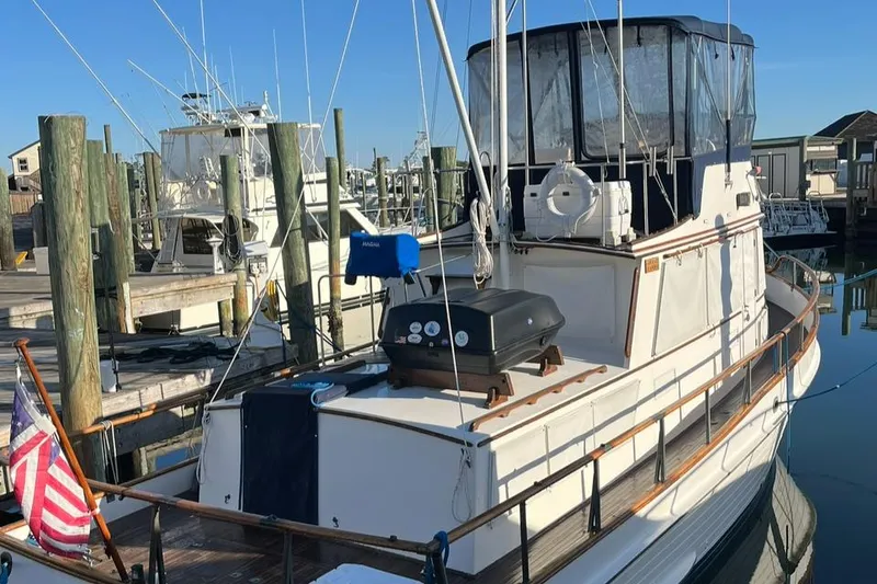 Slide: The Image of 1978 Grand Banks 38 yacht docked at marina with American flag and grill on deck. - 5