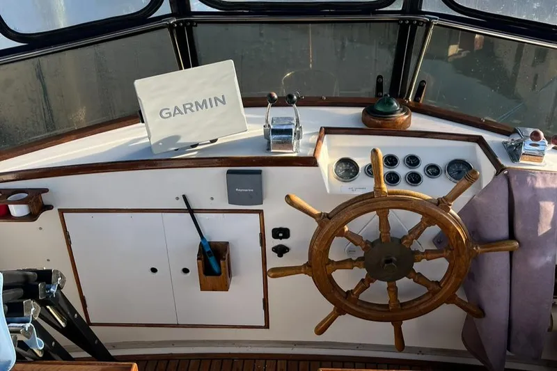 Slide: The Image of 1978 Grand Banks 38 helm with Garmin navigation, wooden wheel, and classic controls. - 8