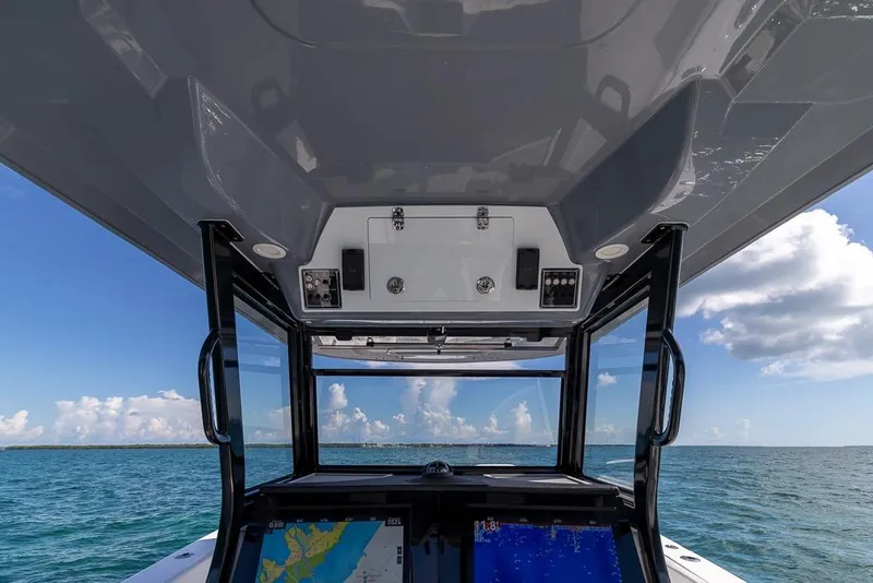 Slide: The Image of 2025 Sea Fox 368 Commander helm view with navigation screens, under a clear blue sky. - 26