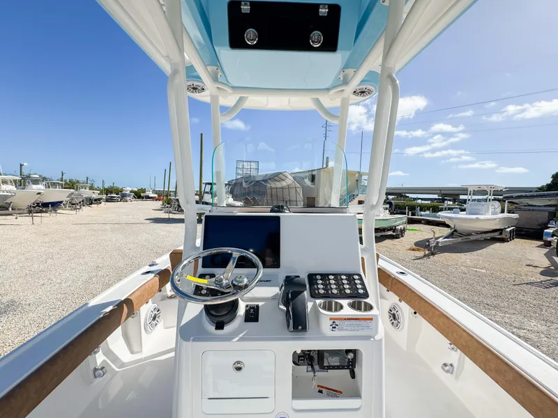 Slide: The Image of 2024 Caymas 26 HB boat console with steering wheel and controls, docked under clear sky. - 16