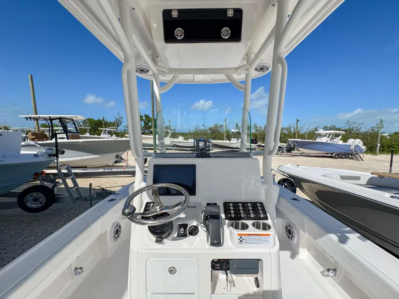 Slide: The Image of 2024 Caymas 26 HB boat console with steering wheel and navigation equipment, docked under clear blue sky. - 13