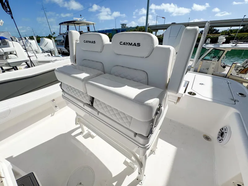 Slide: The Image of 2024 Caymas 26 HB boat with cushioned seating, docked under a clear blue sky. - 23