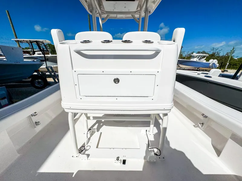 Slide: The Image of 2024 Caymas 26 HB boat interior with white console and storage, under clear blue sky. - 9