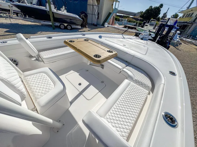 Slide: The Image of 2024 Caymas 28 HB boat interior with white seating and wooden table. - 19