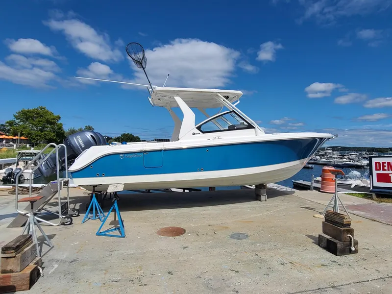 The Image of 2018 Edgewater 262 CX boat on dry dock, blue and white hull, sunny day. - 0