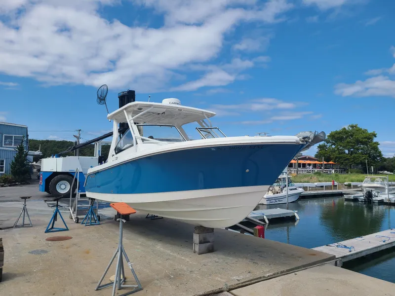 Slide: The Image of 2018 Edgewater 262 CX boat on dock, blue hull, marina background. - 1
