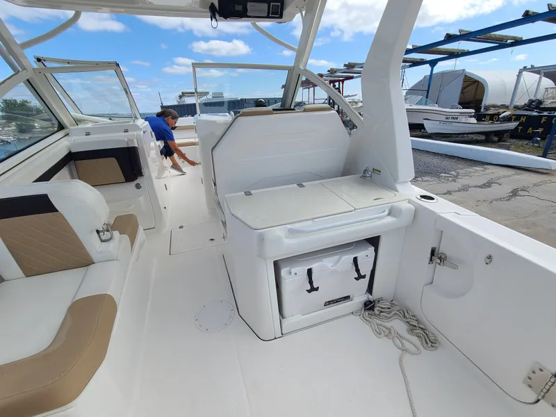 Slide: The Image of 2018 Edgewater 262 CX boat interior with seating and storage, docked under a blue sky. - 15