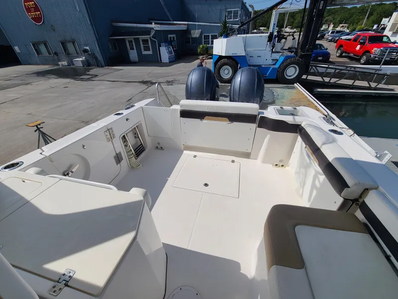 Slide: The Image of 2018 Edgewater 262 CX boat interior with seating and dual engines at a marina. - 17