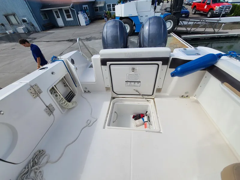 Slide: The Image of 2018 Edgewater 262 CX boat deck with storage compartment and twin outboard motors. - 18