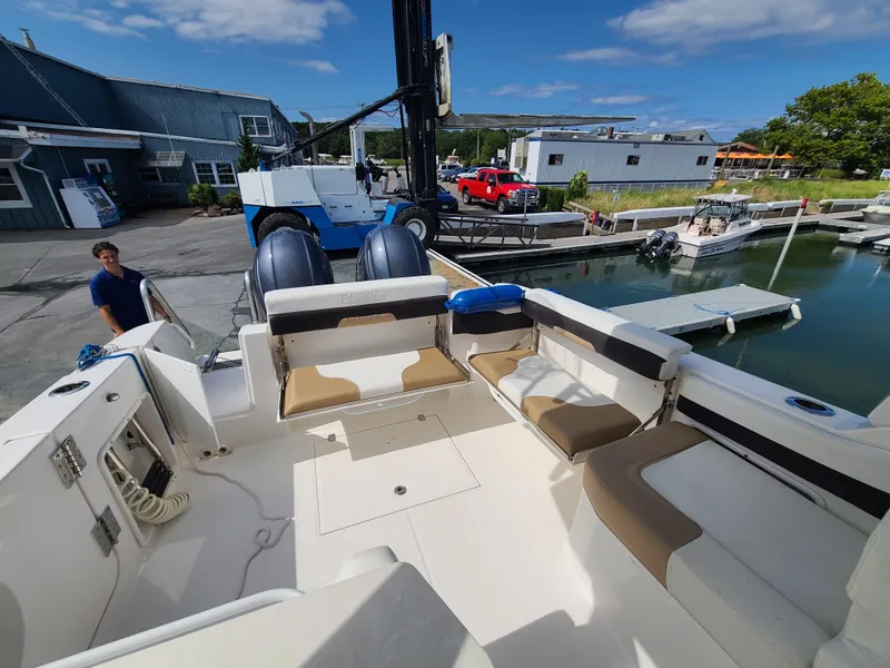 Slide: The Image of 2018 Edgewater 262 CX boat docked at marina with seating area and clear sky. - 2