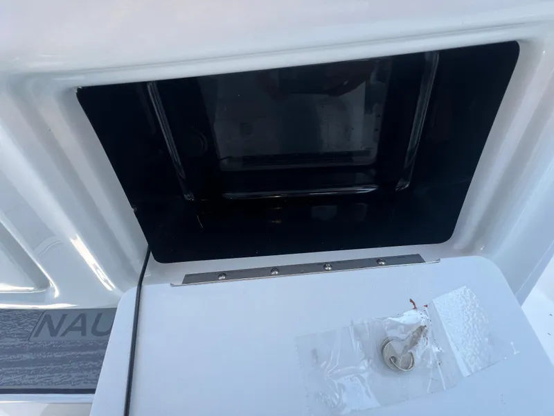 Slide: The Image of 2025 NauticStar 252L boat compartment with key and protective cover. - 20