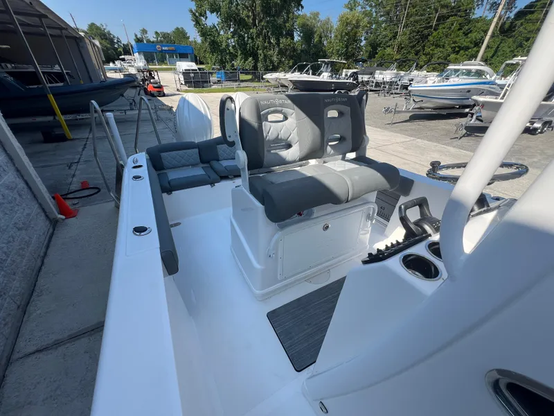 Slide: The Image of 2025 NauticStar 252L boat interior with gray seating and console, docked outdoors. - 33