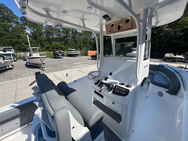 Slide: The Image of 2025 NauticStar 252L boat interior with dual seats and control panel in a marina setting. - 14