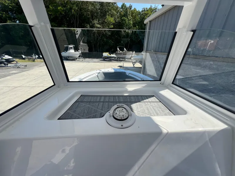 Slide: The Image of 2025 NauticStar 252L boat interior with windshield view, docked at marina. - 17