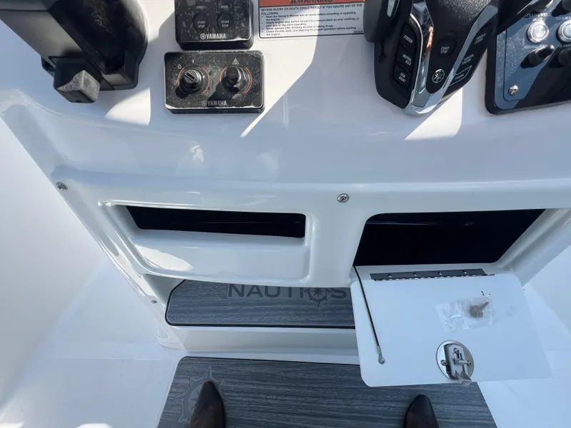 Slide: The Image of NauticStar 252L 2025 boat dashboard with controls and storage compartments. - 19