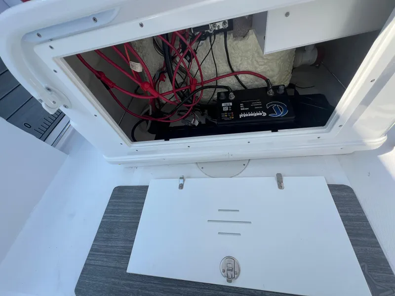 Slide: The Image of Open battery compartment of 2025 NauticStar 252L boat, showing wiring and battery setup. - 22