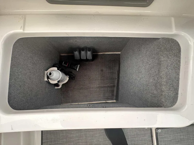 Slide: The Image of Storage compartment in 2019 Chaparral 244 Sunesta boat, featuring a clean, carpeted interior. - 10