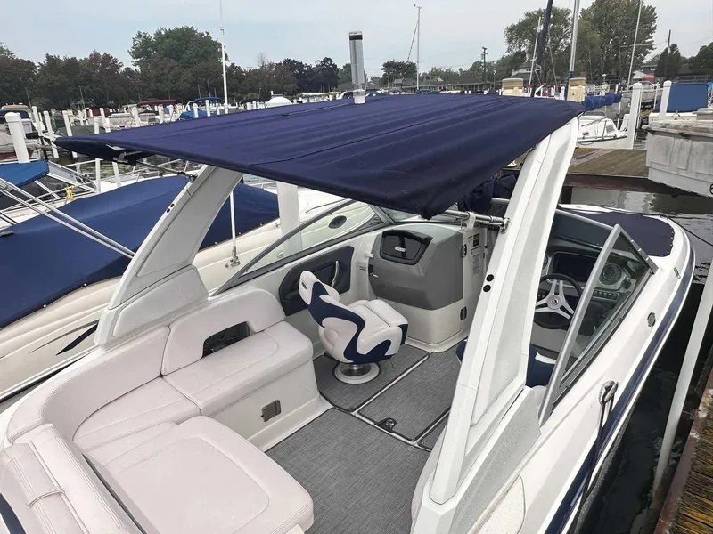 Slide: The Image of 2019 Chaparral 244 Sunesta boat with blue canopy and white seating at marina. - 12