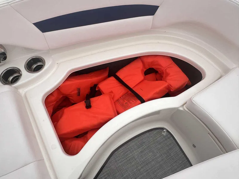 Slide: The Image of Storage compartment with orange life jackets in a 2019 Chaparral 244 Sunesta boat. - 30