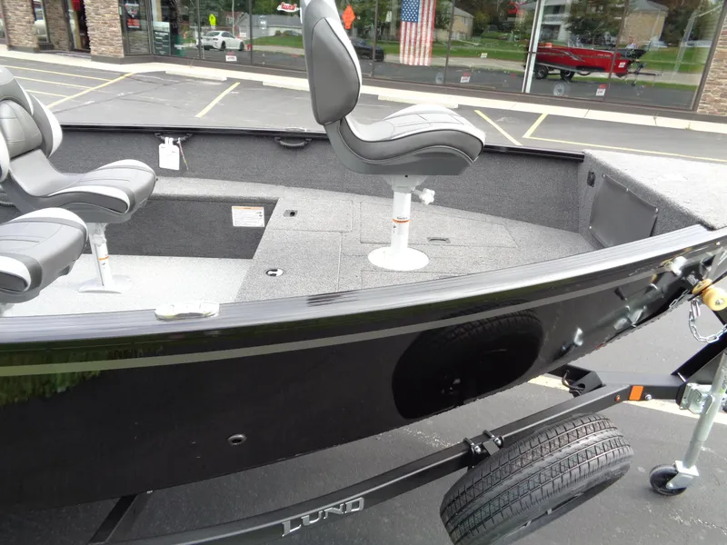 Slide: The Image of 2025 Lund 1650 Rebel XL Tiller boat interior with seating, parked outdoors. - 9